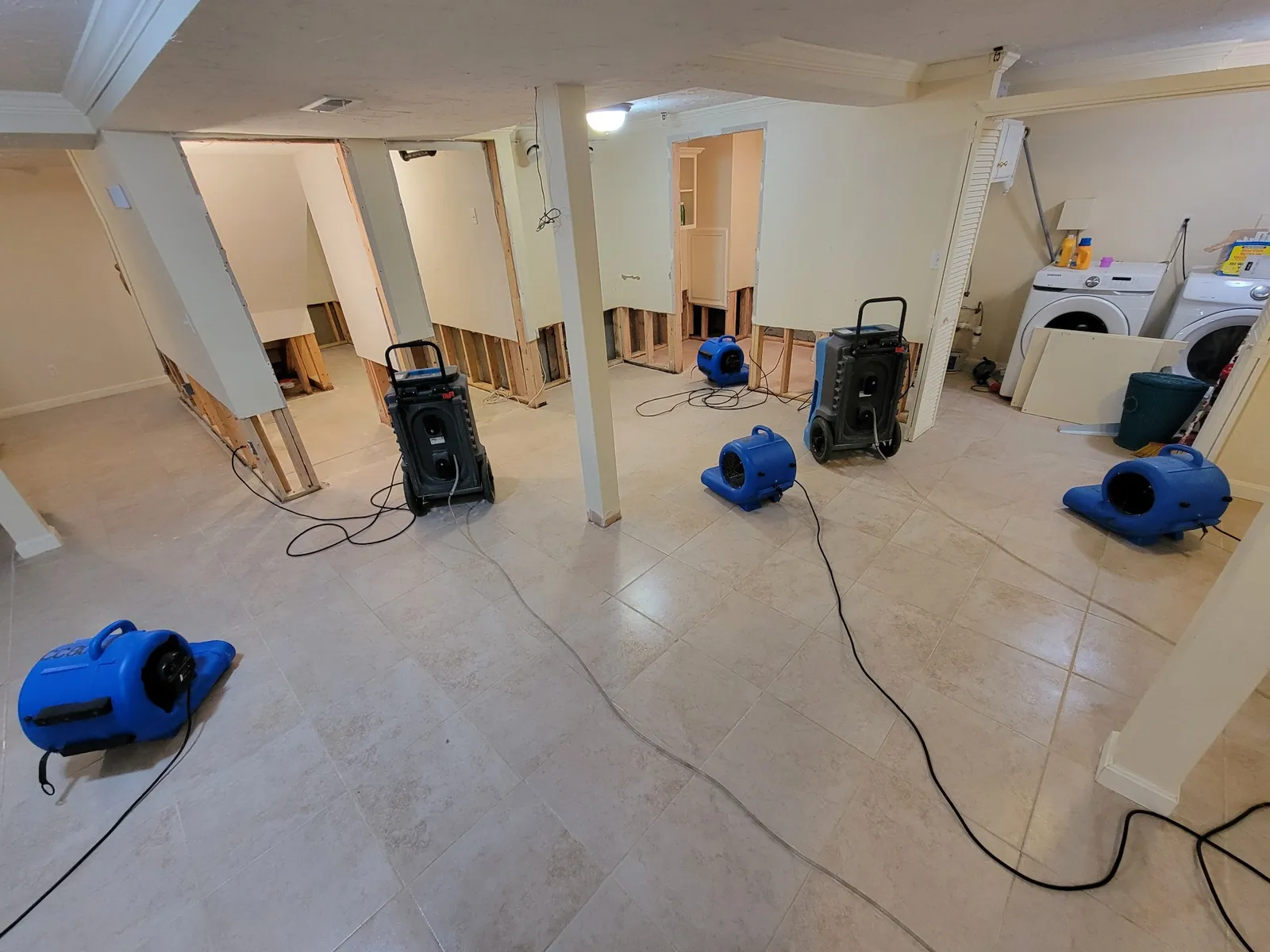 Air movers and a dehumidifier drying a residential room.
